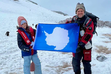 Father and daughter holding Antarctic flag in the snow
