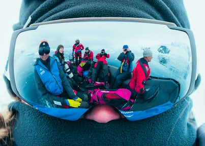 Groups of Antarctic tourists in a zodiac reflected in a pair of goggles