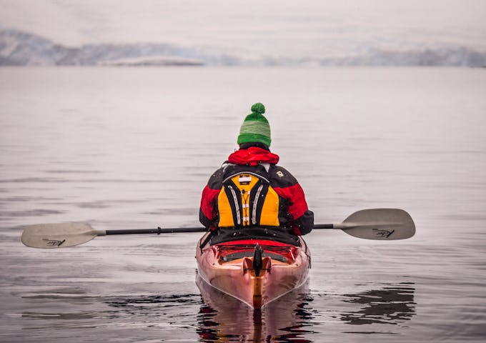 A kayaker glides across placid polar waters in Antarctica 