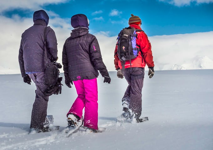 Three polar travellers snowshoe across thick snow in Antarctica 