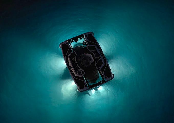 An eerie interplay of light and dark forms outside a submarine sinking into the sea