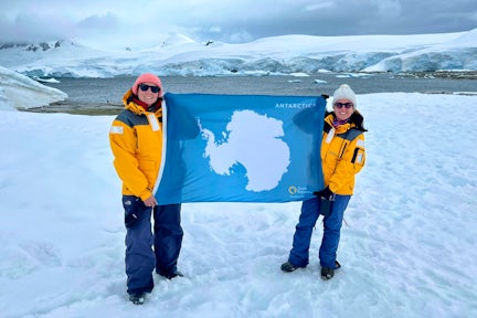 Two tourists flying the Antarctic flag on the 7th Continent