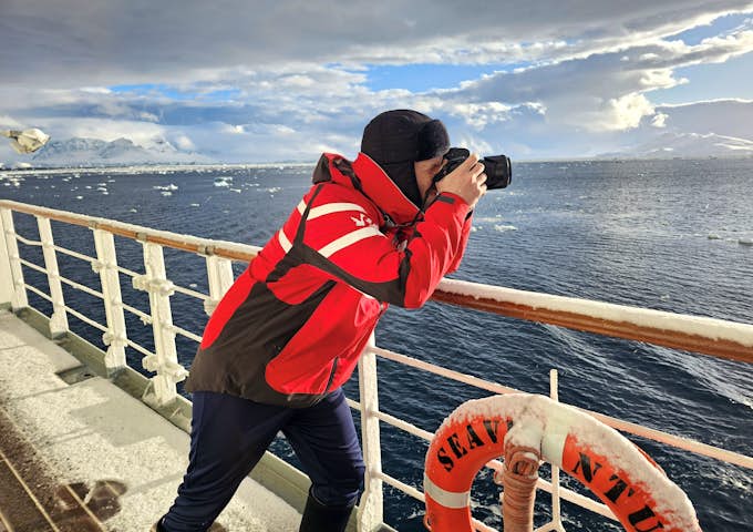 Colin from Swoop takes a photo of Antarctica from out on the deck of a ship 