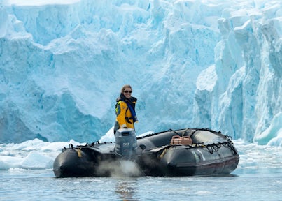 Antarctic expedition guide piloting a zodiac near an iceberg