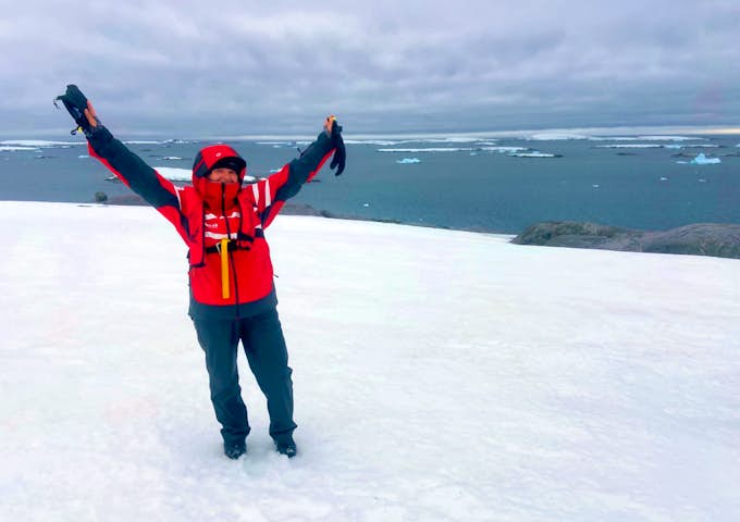 A woman holds her hands up to the sky in Antarctica 