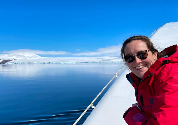 A woman smiles for the camera while sailing in Antarctica 
