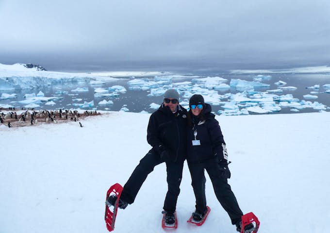 A man and a woman show off their snowshoes in Antarctica 