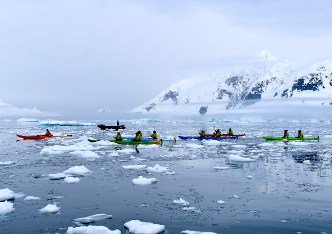Kayakers paddle among the ice in Antarctica on a calm day 
