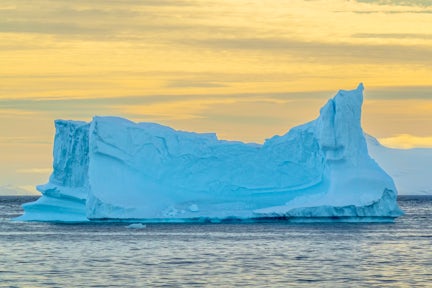 Blue iceberg in Antarctica at sunset