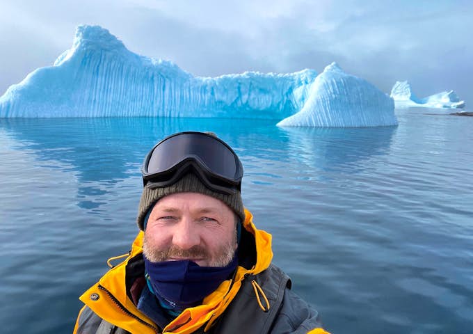 A man takes a selfie with beautiful blue ice in the background in Antarctica 